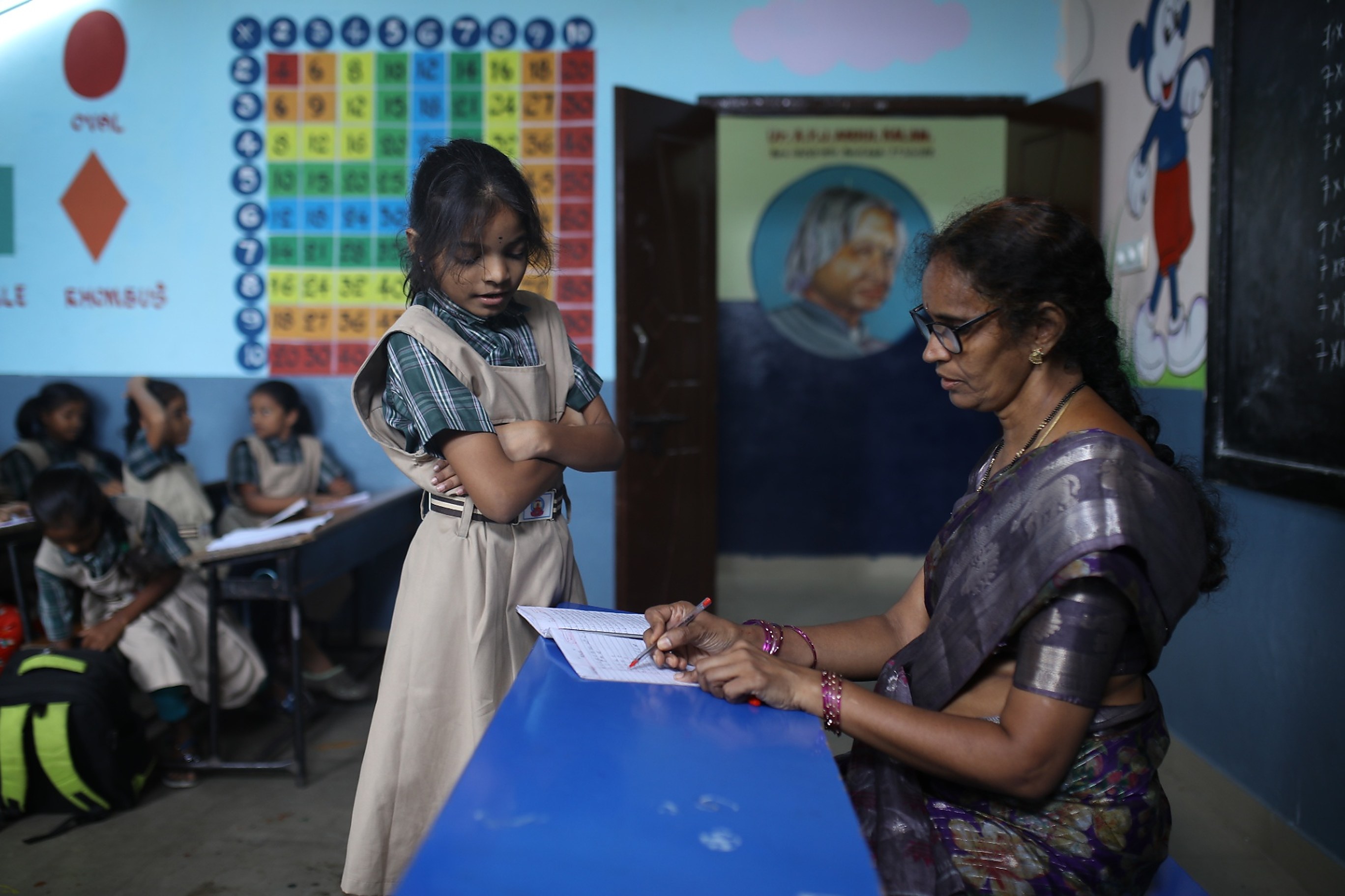 A teacher checking a student's notebook during a free tuition session
